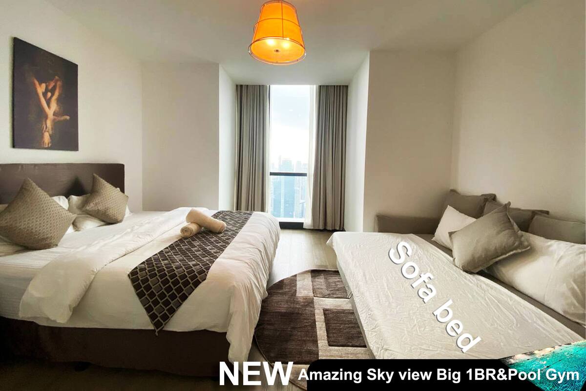 A hotel room with two beds, a sofa bed, a large window with curtains, and a city view.