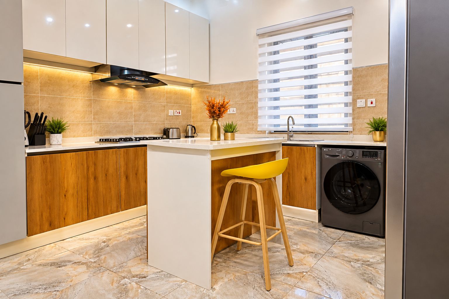 A modern kitchen with a central island, wooden cabinets, a built-in washing machine, and a window with blinds.