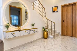 Een modern interieur met een marmeren trap, een ronde spiegel en een houten deur.