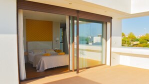 Ein modernes Hotelzimmer mit Bett, Nachttisch und Blick ins Freie.