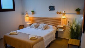 Ein ordentlich eingerichtetes Schlafzimmer mit einem Bett, Nachttischen und dekorativen Pflanzen.