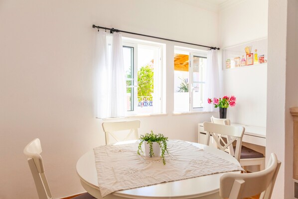 A bright room with a round table, white chairs, and a potted plant.