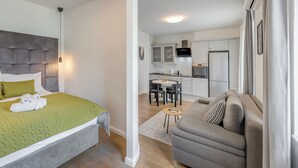 A modern bedroom with a bed, a grey sofa, and a small dining area with a table and chairs. - Finn Luxury Rooms (Split)
