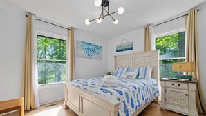 A bedroom with a bed, a nightstand, a lamp, and a window with curtains.