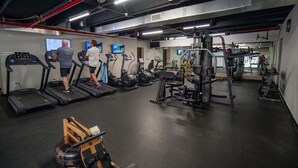Une salle de sport équipée de tapis de course, de vélos elliptiques et de matériel de musculation.