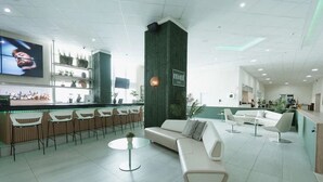 Un hall d’entrée moderne doté d’un bar, de différents espaces de détente et d’un grand écran.