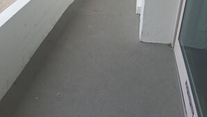 Un balcon donnant sur un parking, avec un bâtiment en arrière-plan et un ciel dégagé.