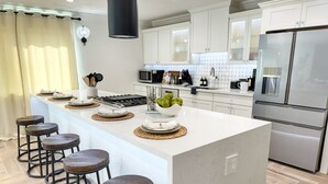 A modern kitchen with a central island, bar stools, and stainless steel appliances.