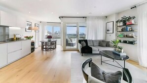 A modern living room with a sofa, a dining table, and a kitchen area. - 2 Bed | Canary Wharf | Stunning Views (London)