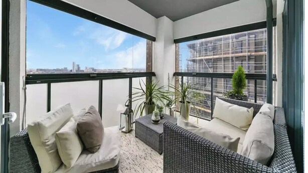 A balcony with wicker furniture, potted plants, and a view of the cityscape. - 2 Bed | Canary Wharf | Stunning Views (London)