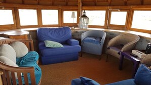 A cozy interior with a blue sofa, a wicker chair, and a wooden chair.