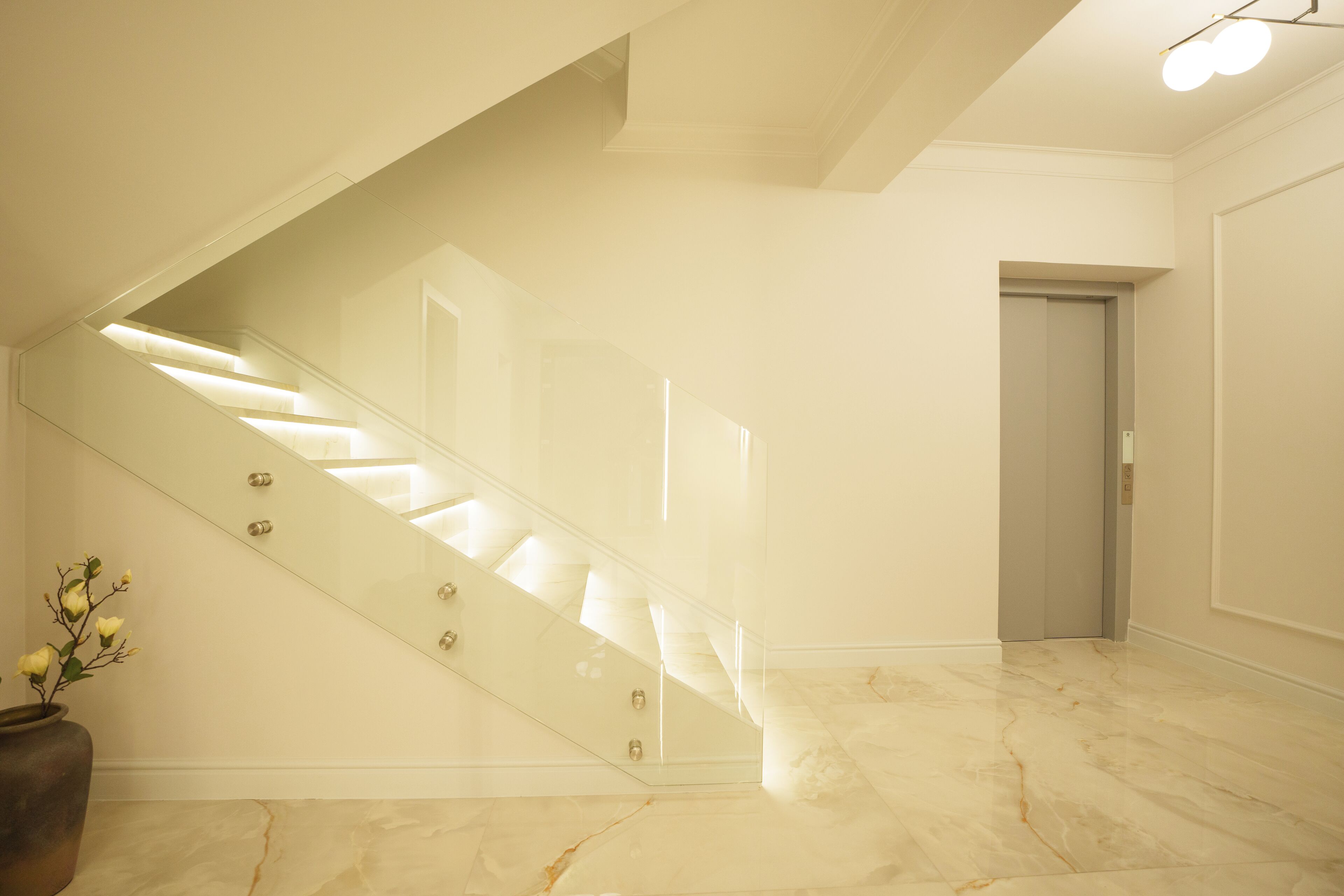 A modern interior with a marble staircase, a potted plant, and a door leading to another room.