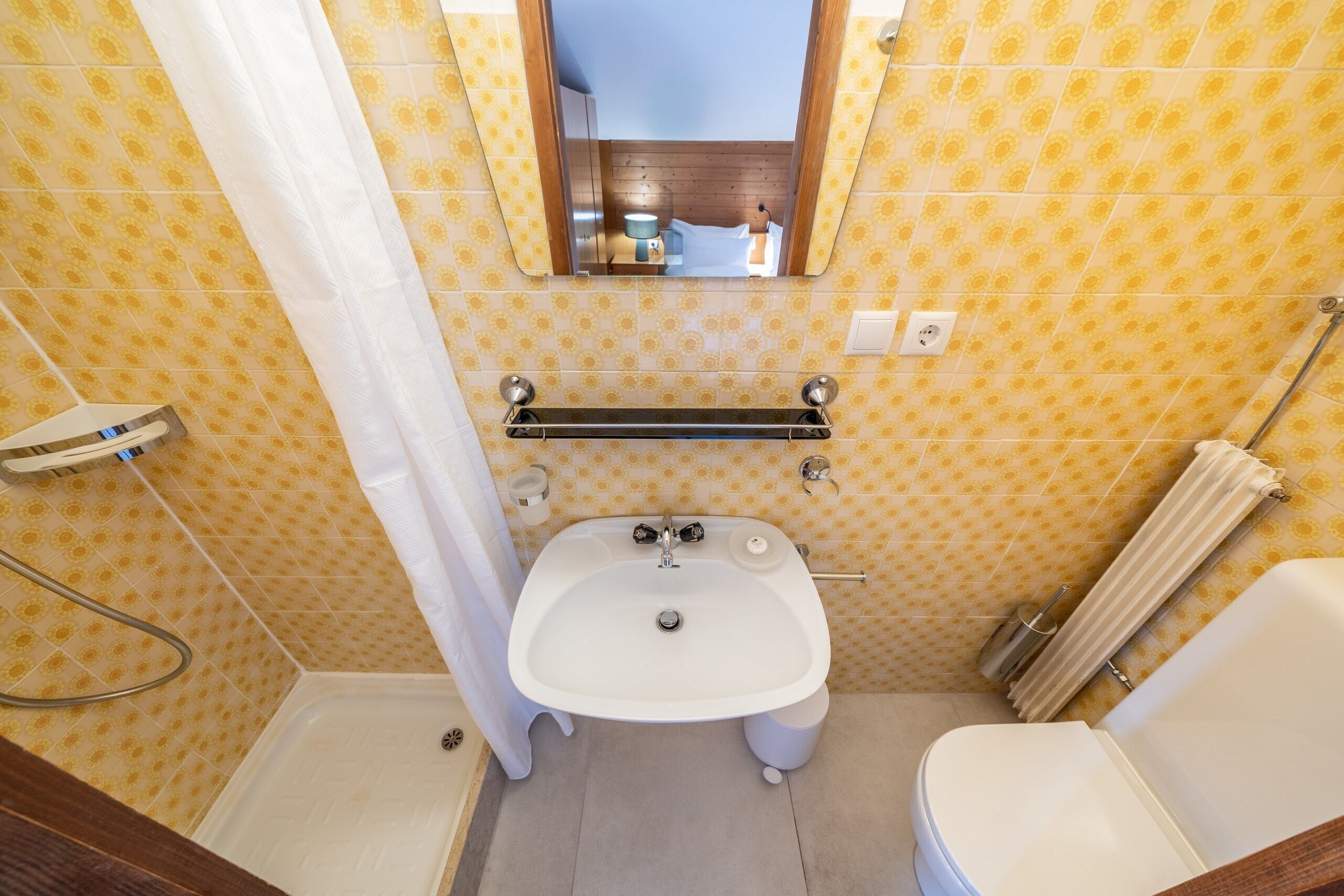 Un baño pequeño con lavamanos, inodoro y ducha blancos.