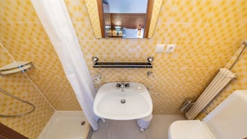 Un baño pequeño con lavamanos, inodoro y ducha blancos.