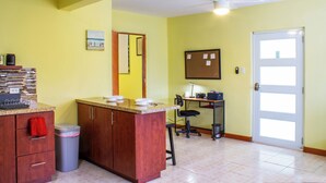 A kitchen with a wooden counter, a trash bin, a ceiling fan, and a door.