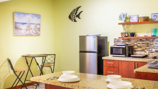 A kitchen with a refrigerator, microwave, and a dining area with chairs and a table.