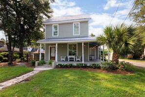 A two-story house with a porch, a small garden, and a pathway leading to the entrance.