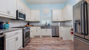 A modern kitchen with white cabinets, stainless steel appliances, and a patterned floor.
