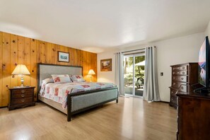 Une chambre à coucher avec un lit, des murs en bois, une commode et un téléviseur.