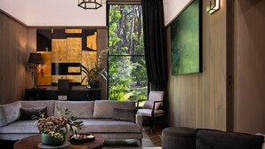 Una sala de estar moderna con un sofá, sillones, una mesita de centro y un ventanal con vistas a un bosque.