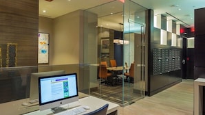 Un espacio de oficina moderno con separadores de vidrio, un ordenador de escritorio y una sala de reuniones visible a través de los separadores.