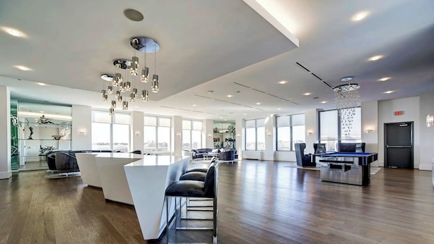 Un lobby de hotel espacioso y moderno con un mostrador de recepción central, varias zonas de estar y grandes ventanales con vistas a la ciudad.