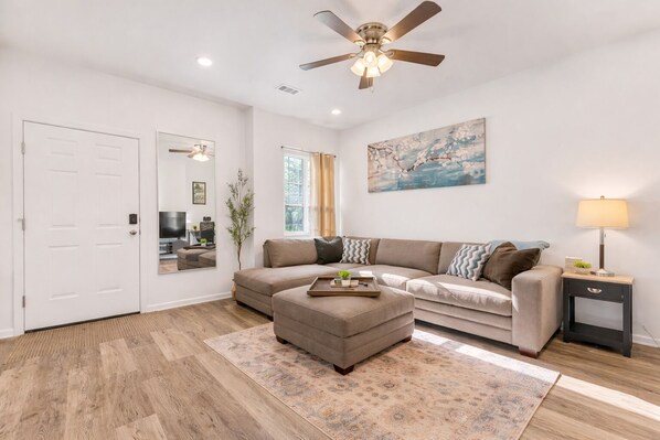 A living room with a sofa, ottoman, and a lamp.