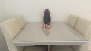 Een eettafel met vier stoelen, een klein decoratief object in het midden en een rode hoed aan de muur.