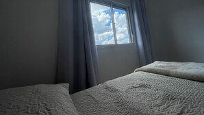 Een slaapkamer met een raam, twee bedden en gordijnen.