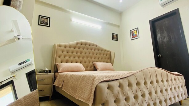 Een slaapkamer met een gebonden bed, een nachtkastje, een ventilator in het plafond en een airconditioning.