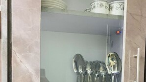 Un meuble de cuisine doté d’étagères où sont rangés divers ustensiles, notamment un récipient hermétique, un bocal en verre et une boîte en métal.