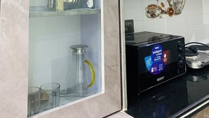 Une cuisine équipée d’un four à micro-ondes, d’un meuble contenant des ustensiles et d’un crédence décorative en carreaux.