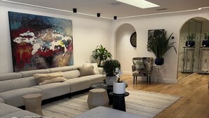 Un salon moderne avec un grand canapé d’angle, une table basse et un tableau accroché au mur.