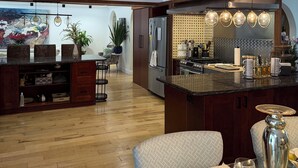 Une cuisine moderne dotée d’un îlot central, de poutres en bois et d’un coin repas avec une table dressée pour deux personnes.
