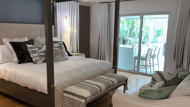 Une chambre à coucher avec un lit à baldaquin, un banc, un canapé et une vue sur l’extérieur.