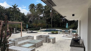 Un espace patio aménagé avec des meubles en osier et une piscine.