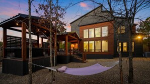 Una casa moderna con terraza de madera, una hamaca y un área de estar techada.