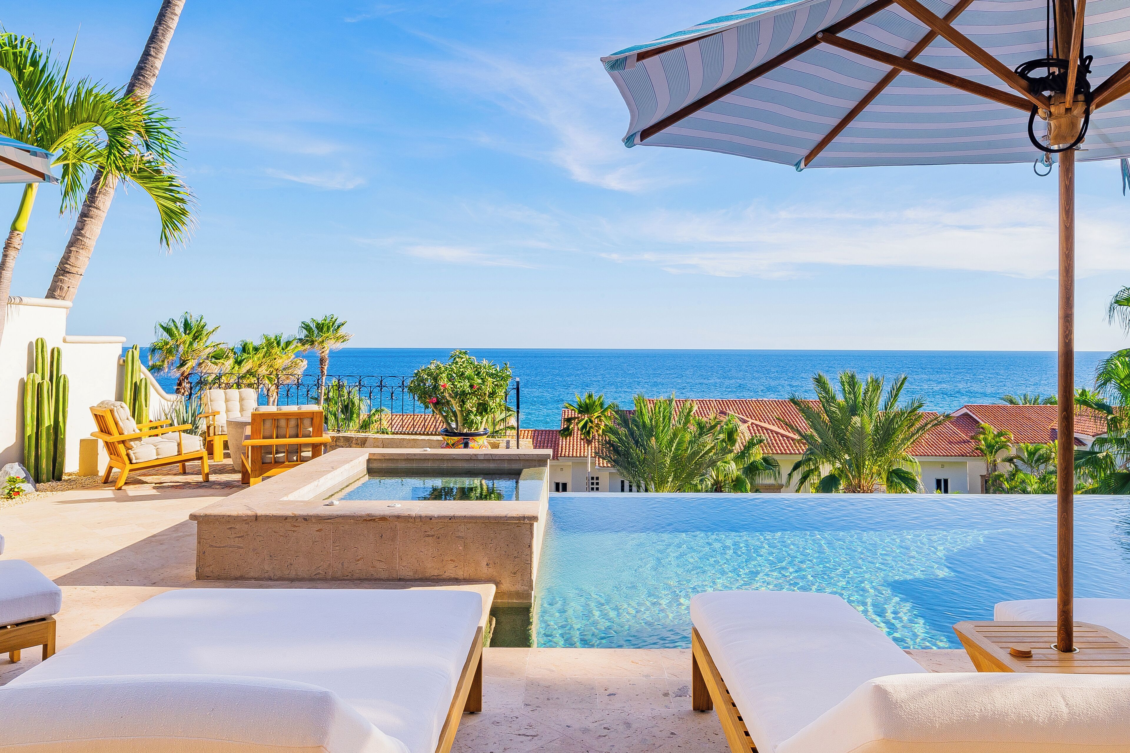 A poolside area with lounge chairs and a view of the ocean.