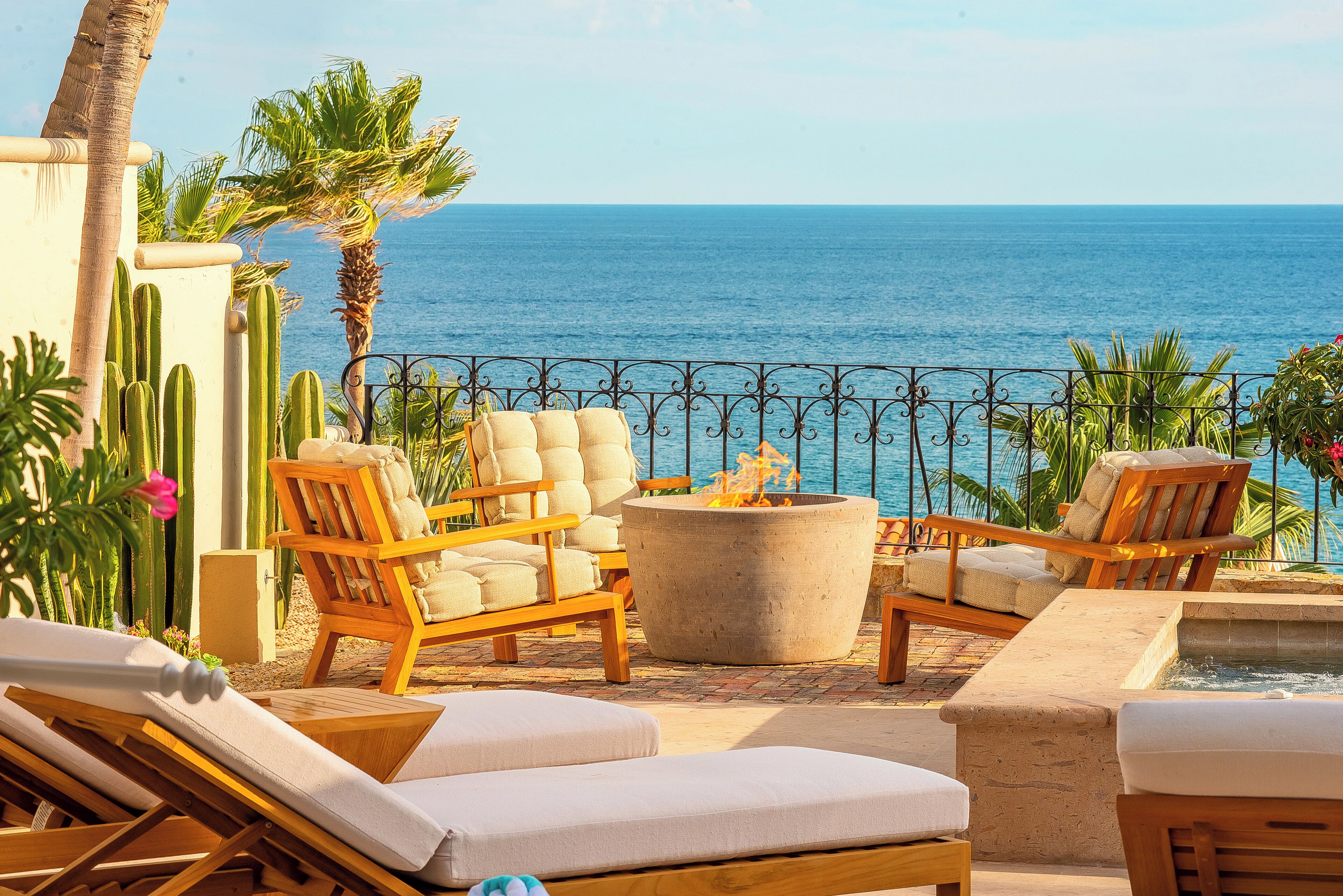 A terrace with wooden lounge chairs, a fire pit, and a view of the ocean.
