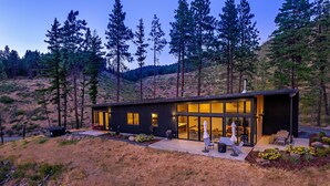 Una casa moderna con patio, ampie finestre e vista sulla foresta circostante.