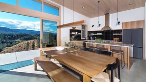 Una cucina moderna con una grande isola, arredi in legno e vista su un paesaggio montuoso.