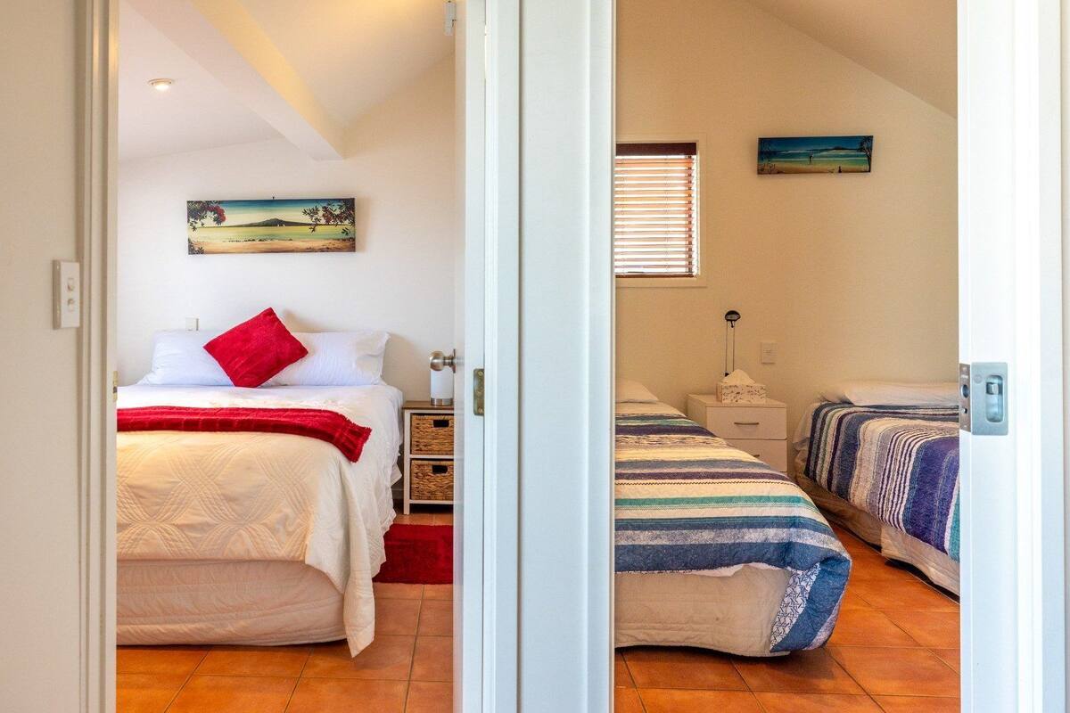 A bedroom with a bed, a nightstand, a lamp, and a window with blinds.