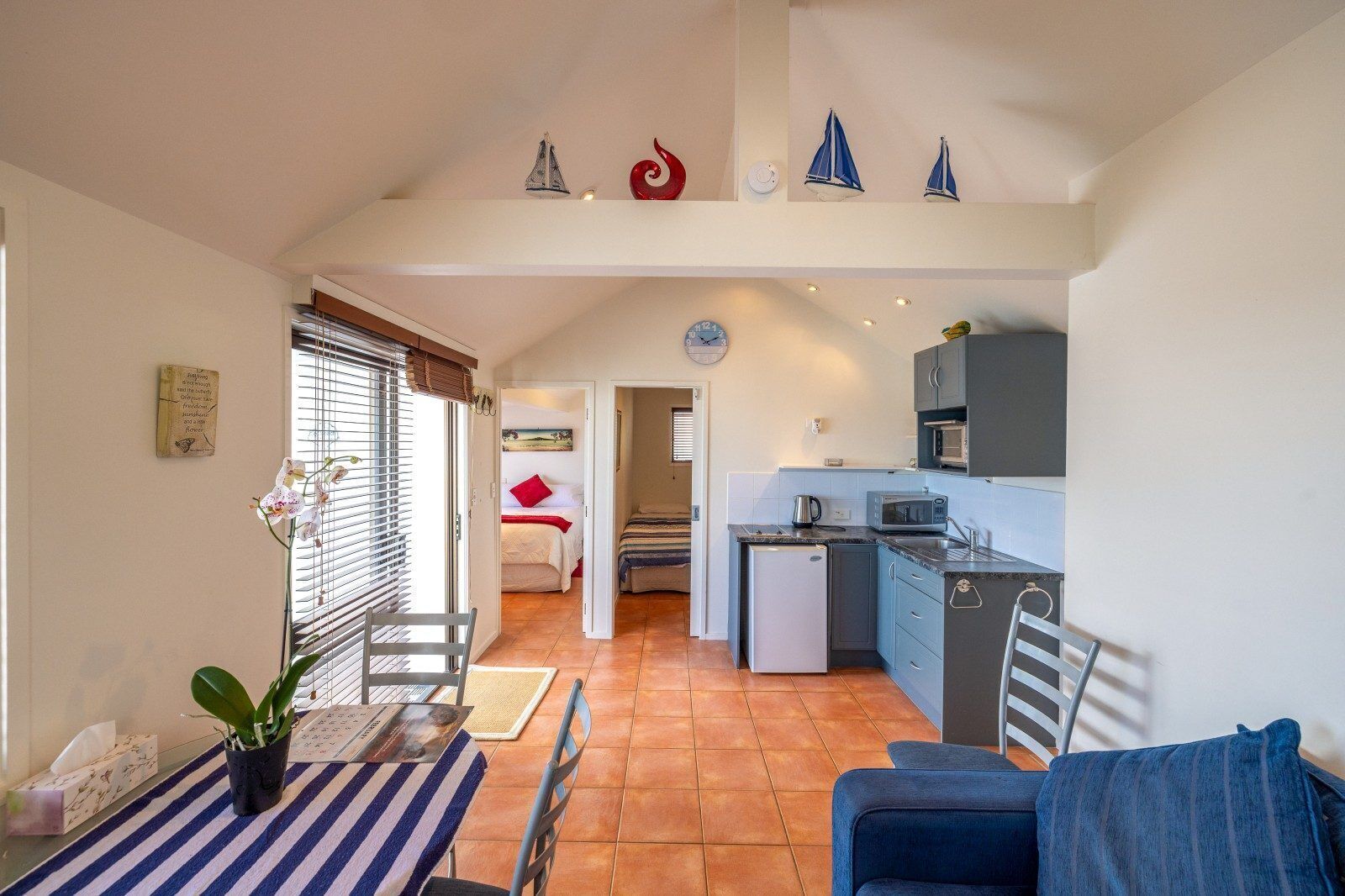 Un espacio habitable compacto con comedor, cocina y un dormitorio con una pared de acento roja.