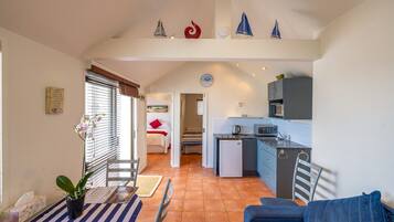 Un espacio habitable compacto con comedor, cocina y un dormitorio con una pared de acento roja.