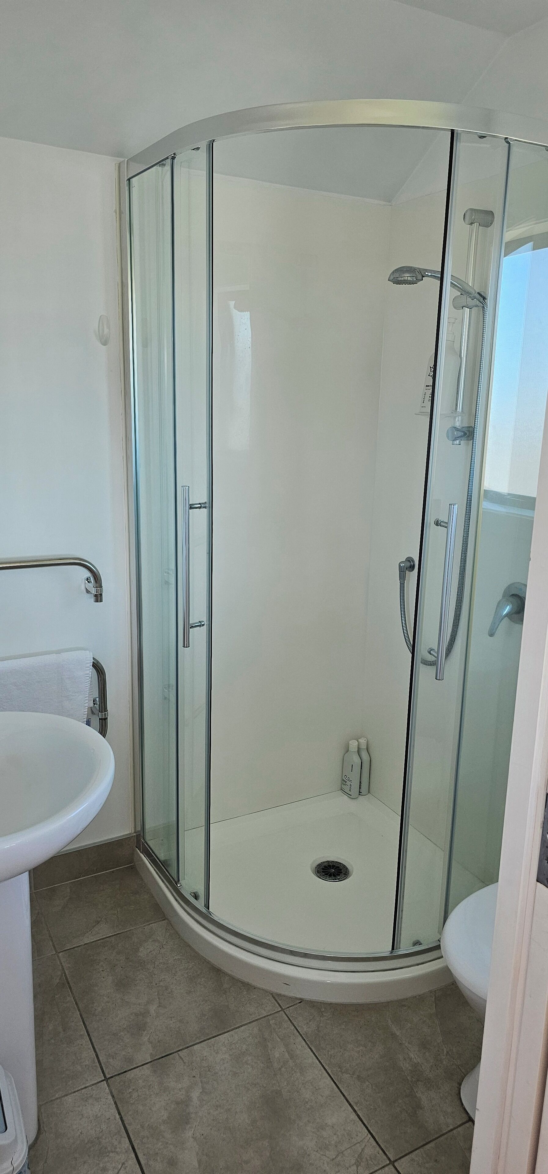 A modern bathroom with a glass-enclosed shower, a white sink, and a toilet.