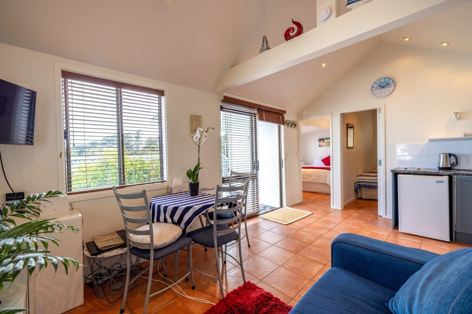 A compact living space with a dining area, kitchenette, and a bedroom.