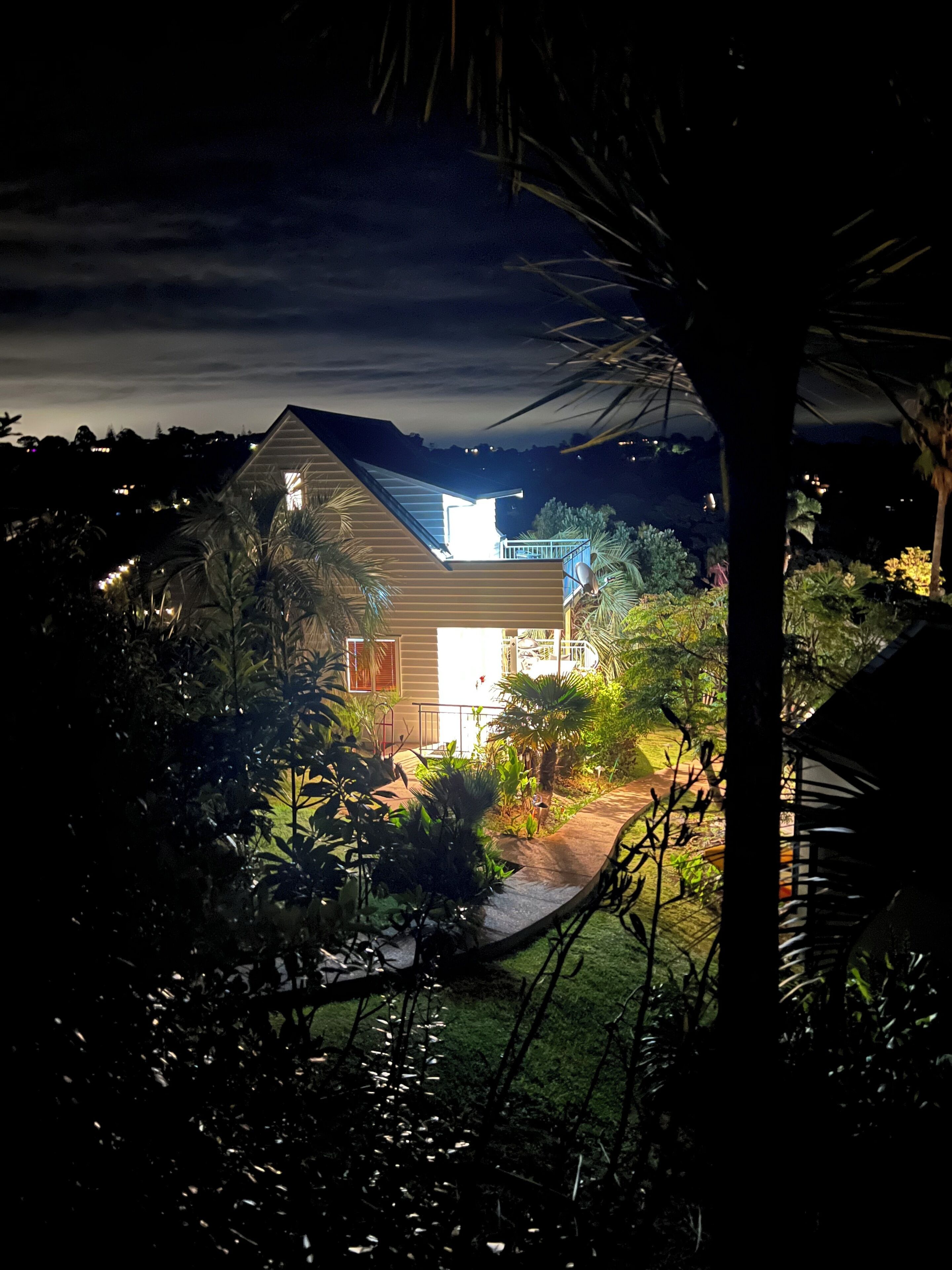 A house with a sloped roof, surrounded by lush greenery and a well-maintained garden.