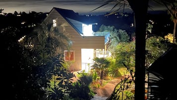 A house with a sloped roof, surrounded by lush greenery and a well-maintained garden.