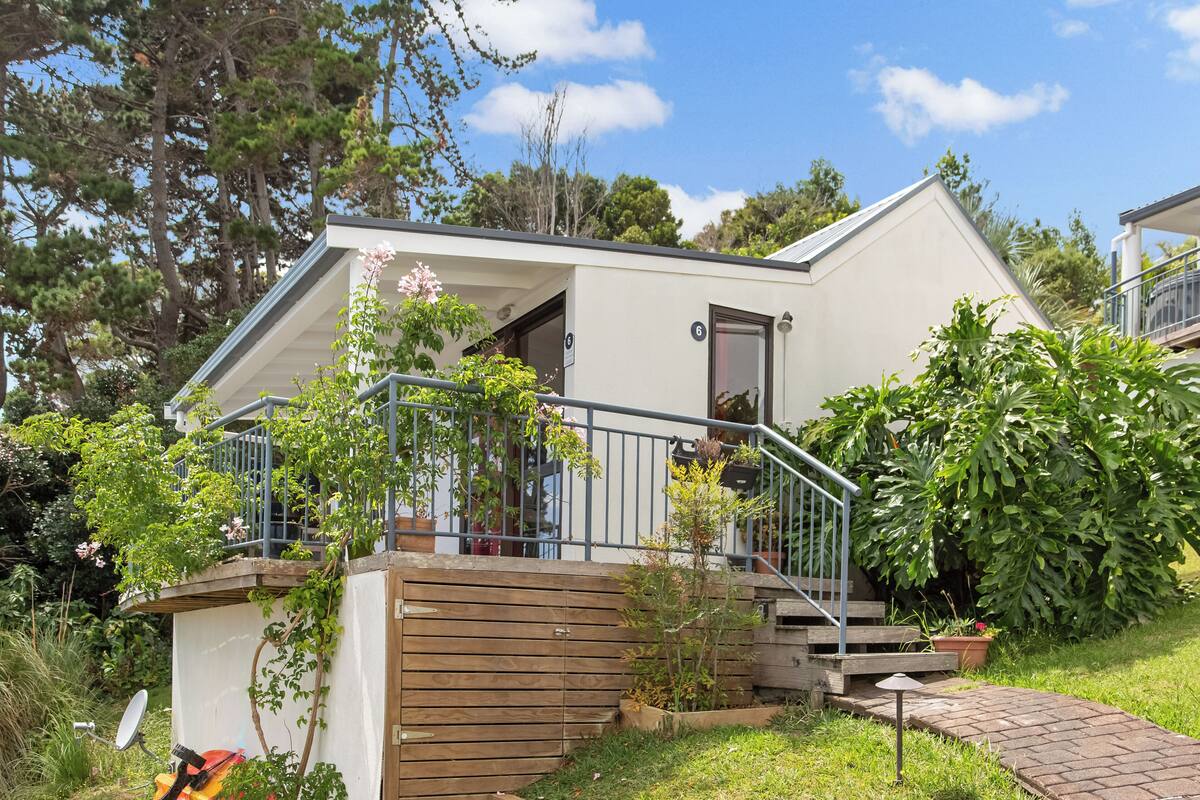 A single-story house with a wooden deck, a small porch, and a staircase leading to the entrance.