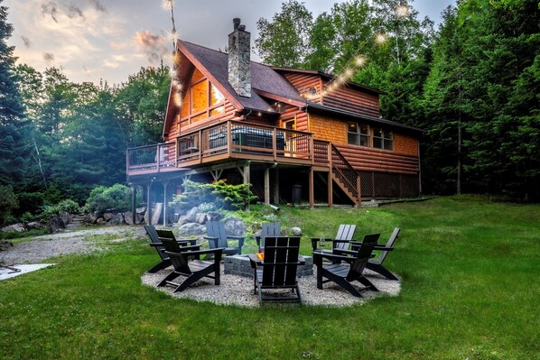 Une cabane en rondins dotée d’une terrasse, d’un espace salon extérieur et d’un foyer.